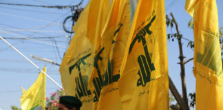 Men standing with yellow flags wearing green berets
