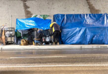 Two people with tarps and shopping carts outdoors