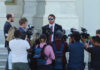 Group of reporters surrounding a man in sunglasses
