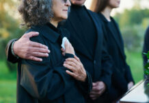 People comforting each other at a funeral outdoors