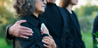 People comforting each other at a funeral outdoors