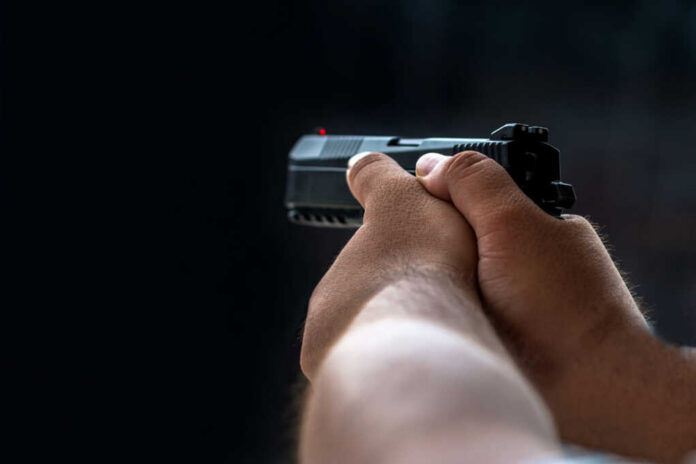 man-aiming-pistol1119308795jpg Person holding a black handgun in firing position
