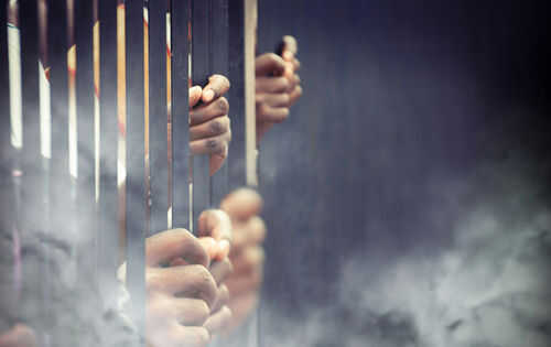 Hands gripping prison bars in smoky atmosphere