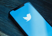 Close-up of a smartphone displaying the Twitter logo on a blue background