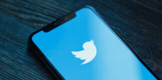 Close-up of a smartphone displaying the Twitter logo on a blue background