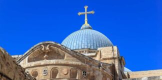 Dome of a historic church with a cross against a clear blue sky