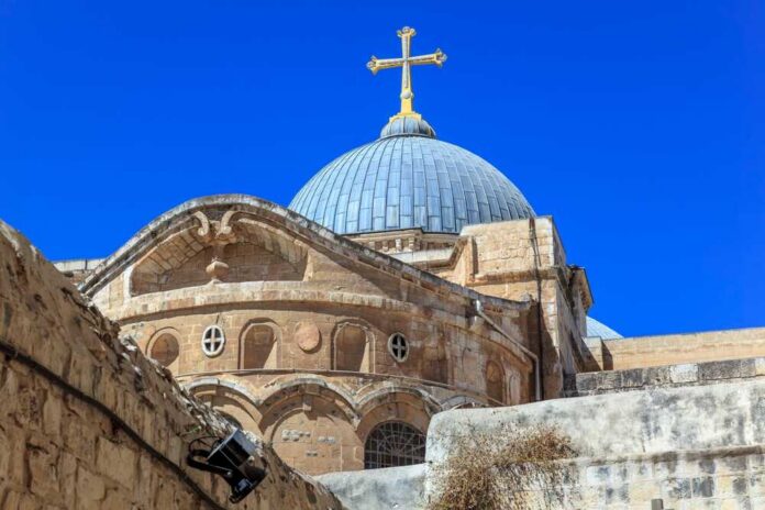 shutterstock_2421078201.jpg Dome of a historic church with a cross against a clear blue sky