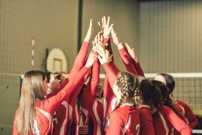 shutterstock_2424970613.jpg Volleyball players celebrating with hands raised together