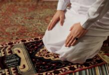 Person kneeling on a prayer rug in traditional attire