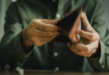 Person holding an open brown wallet, inspecting its contents