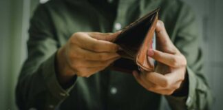 Person holding an open brown wallet, inspecting its contents