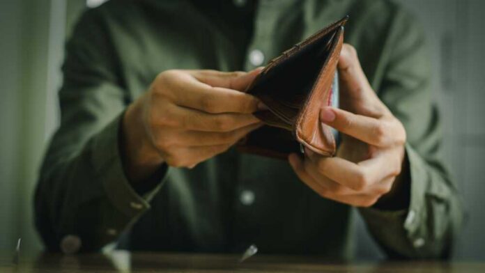 Person holding an open brown wallet, inspecting its contents