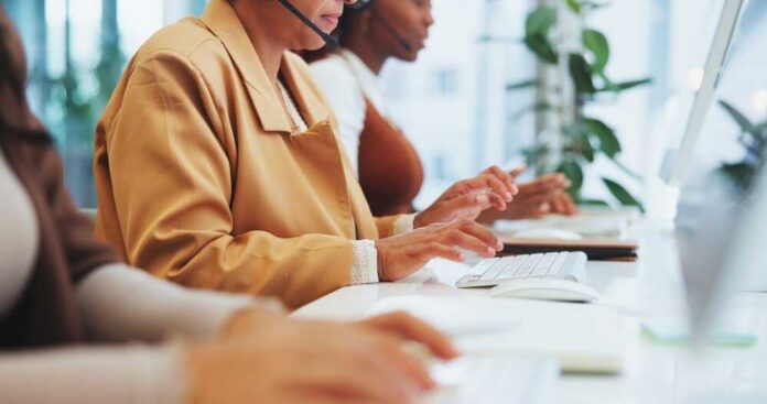 Three women working at a call center, typing on keyboards