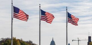 Three American flags waving in front of the Capitol building