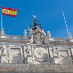 Clock tower of a historic building with the Spanish flag flying