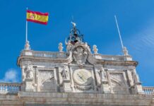 Clock tower of a historic building with the Spanish flag flying