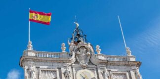 Clock tower of a historic building with the Spanish flag flying