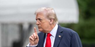 A man in a suit gesturing with his finger during a press conference