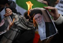 A person holding a burning photograph during a protest