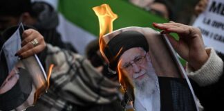 A person holding a burning photograph during a protest