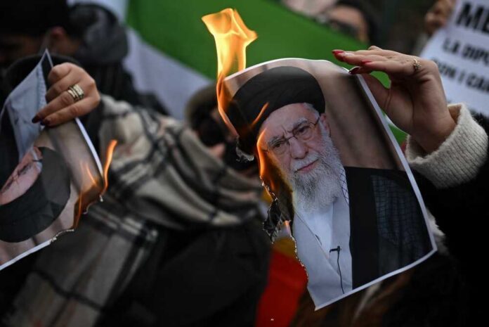 A person holding a burning photograph during a protest