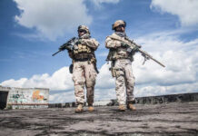 Two soldiers in tactical gear walking in an urban setting