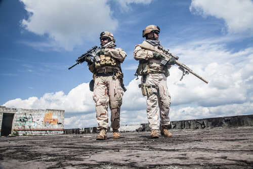 Two soldiers in tactical gear walking in an urban setting