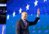 Man in suit waving against starry blue background