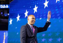 Man in suit waving against starry blue background