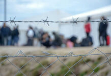 Barbed wire fence in front of blurred people