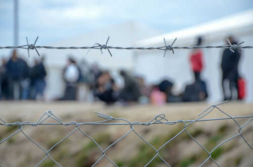 Barbed wire fence in front of blurred people