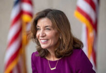 Smiling woman in a purple dress with flags behind