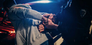 Police officer arresting a person at night.