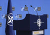 NATO podium with flags and microphones.