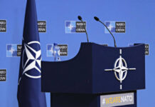 NATO podium with flags and microphones.