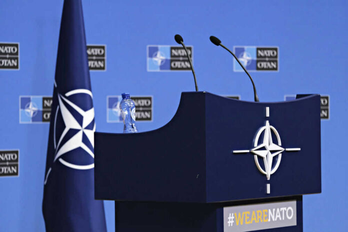 NATO podium with flags and microphones.