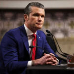 Man in blue suit speaking at a microphone