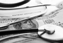 A stethoscope resting on a patient history form and U.S. currency