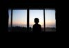 Child’s ICE Detention Sparks National Outrage Silhouette of a child looking out a window at a sunset