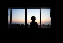 Child’s ICE Detention Sparks National Outrage Silhouette of a child looking out a window at a sunset