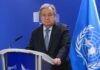 UN Secretary-General at a press conference with the UN flag in the background