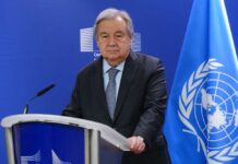 UN Secretary-General at a press conference with the UN flag in the background