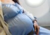 Flight Birth Sparks Legal Chaos Over U.S. Citizenship Pregnant woman seated on an airplane, wearing a blue dress