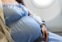 Pregnant woman seated on an airplane, wearing a blue dress