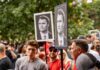 Crowd at a protest holding signs with portraits