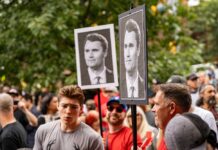 Crowd at a protest holding signs with portraits