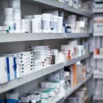 Shelves filled with various medication boxes and containers in a pharmacy