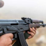 Person holding a rifle outdoors