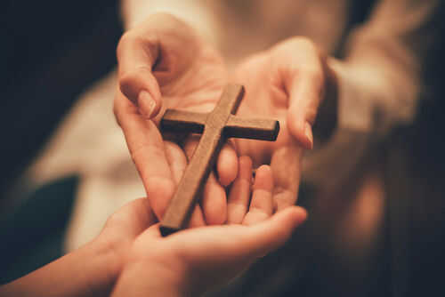 christianity-cross1782167450jpg Hands holding a wooden cross together