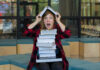 Person balancing books on head, looking surprised.